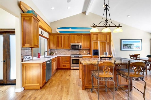 33441 N Spinnaker Dr N, Dana Point, CA 92629 - kitchen featuring appliances with stainless steel finishes, a breakfast bar area, tasteful backsplash, light wood-type flooring, and brown cabinetry
