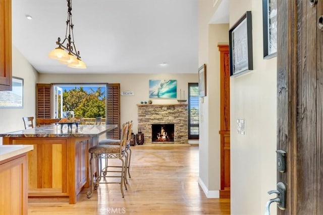 33441 N Spinnaker Dr N, Dana Point, CA 92629 - kitchen with light wood finished floors, a breakfast bar area, decorative light fixtures, a fireplace, and open floor plan