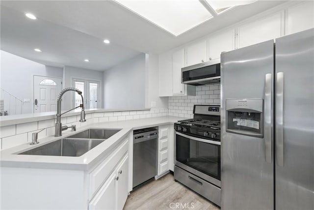 72 S Greenwood Ave Unit 3, Pasadena, CA 91107 - kitchen with appliances with stainless steel finishes, a sink, tasteful backsplash, white cabinetry, and light wood-type flooring