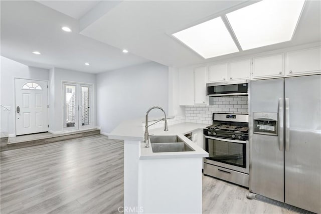 72 S Greenwood Ave Unit 3, Pasadena, CA 91107 - kitchen featuring stainless steel appliances, a sink, a peninsula, light countertops, and light wood finished floors