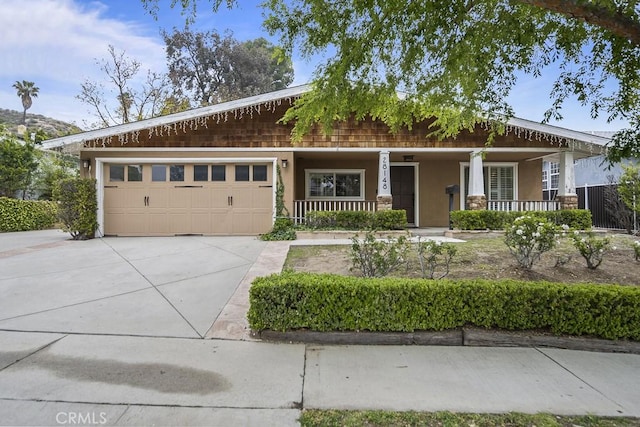 view of front of home with covered porch, driveway, stucco siding, and a garage
