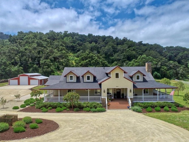 7550 Mary Hall Rd, Arroyo Grande, CA 93420 - farmhouse-style home with covered porch, concrete driveway, a forest view, a detached garage, and a chimney