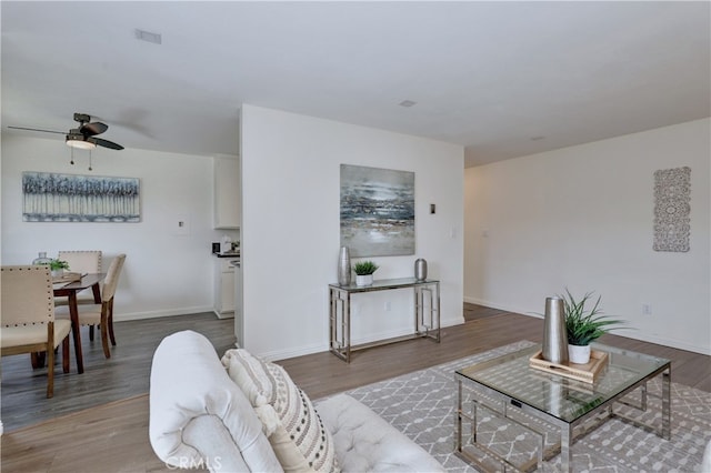 living room with a ceiling fan, wood finished floors, and baseboards