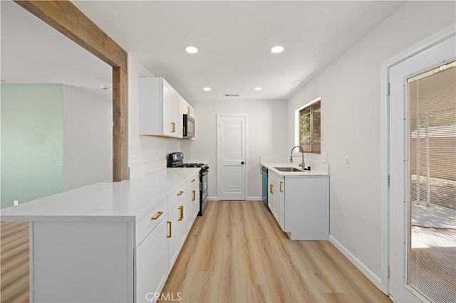 3316 Roxbury St, Rosamond, CA 93505 - kitchen with appliances with stainless steel finishes, a sink, light wood-style flooring, white cabinets, and a peninsula