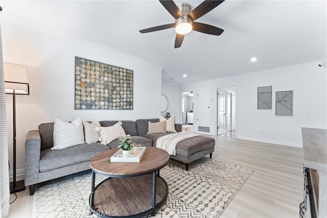living room with crown molding, light wood finished floors, a ceiling fan, baseboards, and recessed lighting
