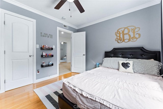 bedroom with light wood-type flooring, ornamental molding, baseboards, and ceiling fan
