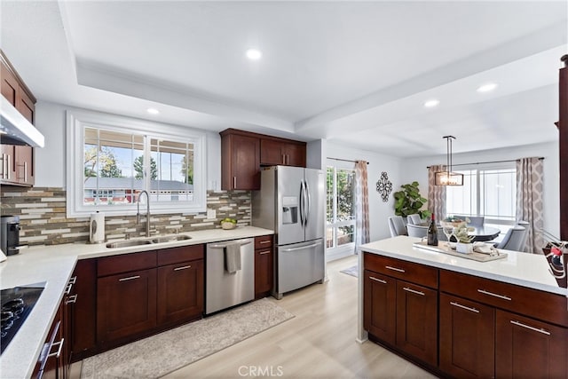 kitchen with stainless steel appliances, a sink, decorative backsplash, light wood-type flooring, and recessed lighting