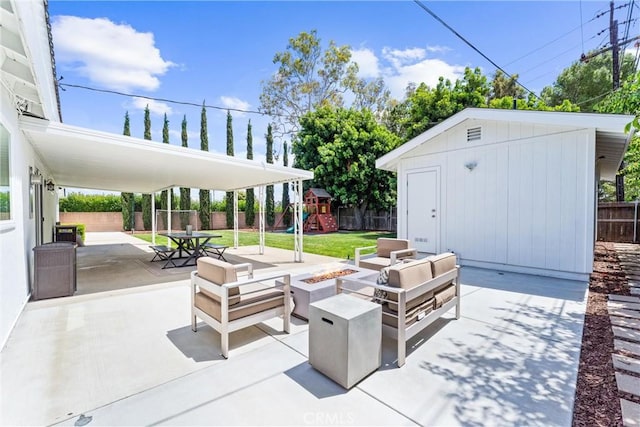 view of patio with a playground, an outbuilding, and an outdoor living space with a fire pit