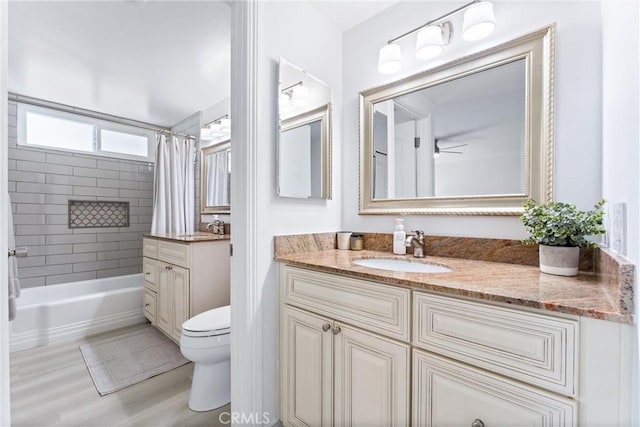full bath featuring toilet, vanity, shower / bath combo, wood finished floors, and a ceiling fan
