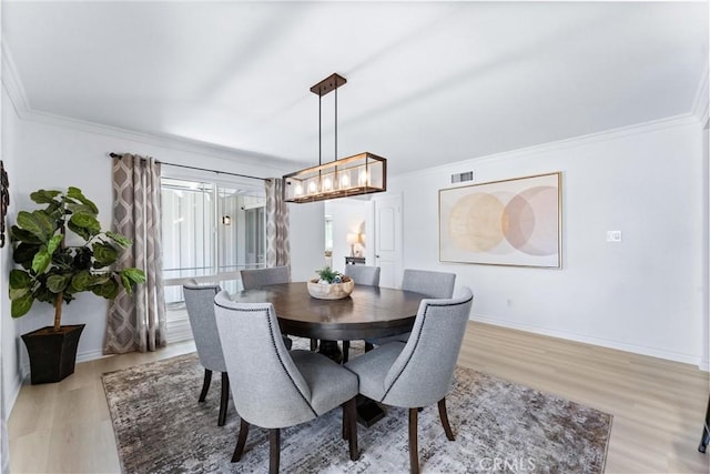dining area with light wood-style floors, ornamental molding, and baseboards