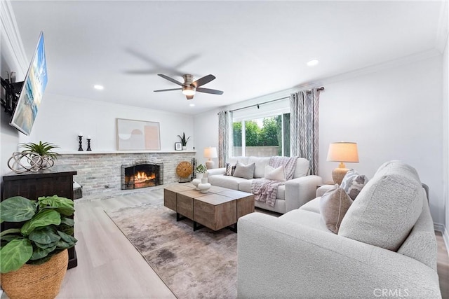 living room featuring wood finished floors, a brick fireplace, ceiling fan, ornamental molding, and recessed lighting