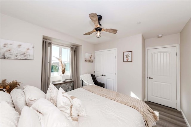 bedroom featuring wood finished floors, a closet, ceiling fan, and baseboards