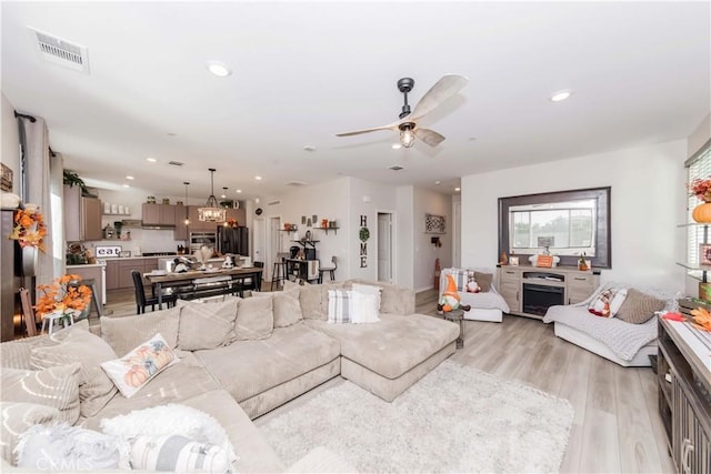 living room featuring light wood-style floors, ceiling fan, recessed lighting, and a chandelier