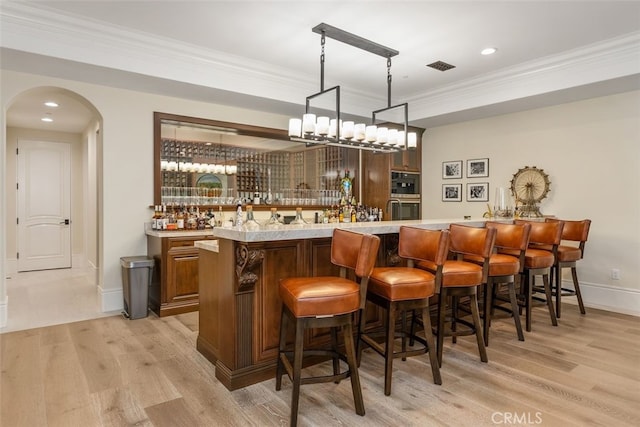 35 Shoreline Dr, Dana Point, CA 92629 - indoor wet bar featuring light wood-style flooring, arched walkways, crown molding, baseboards, and hanging light fixtures