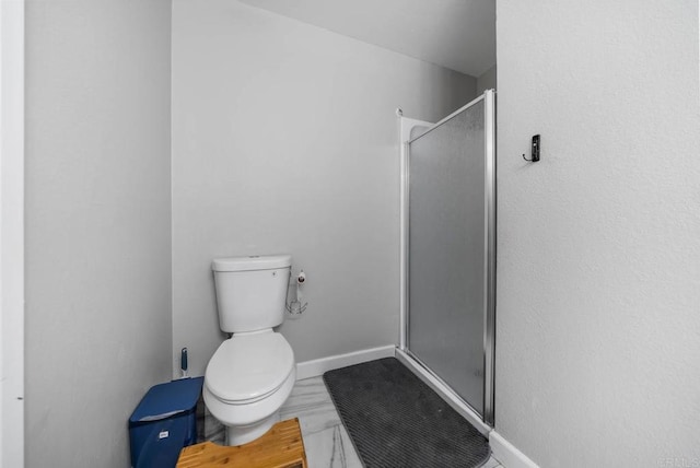 bathroom featuring a stall shower, toilet, and baseboards