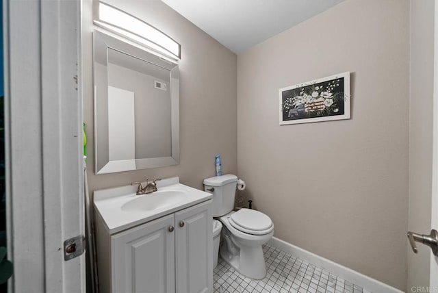 half bathroom with toilet, vanity, tile patterned flooring, and baseboards