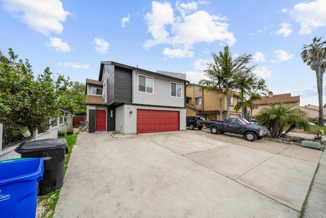 view of front facade featuring an attached garage, stucco siding, driveway, a residential view, and fence