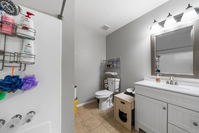 bathroom with toilet, vanity, and tile patterned floors