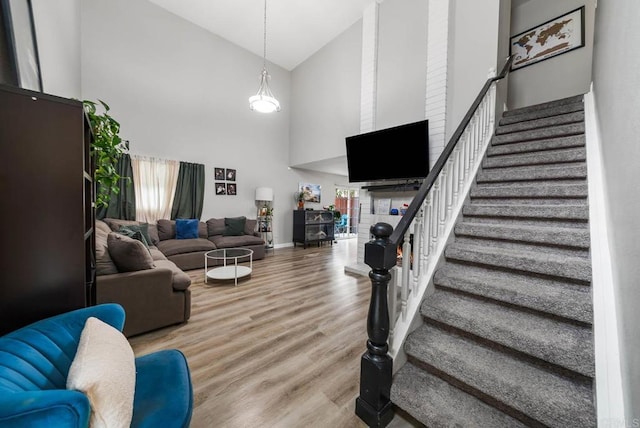 living area featuring high vaulted ceiling, stairs, wood finished floors, and baseboards