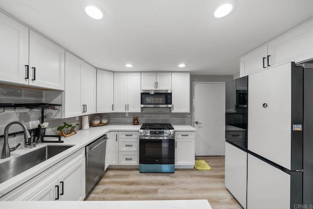 kitchen with stainless steel appliances, a sink, white cabinets, decorative backsplash, and recessed lighting