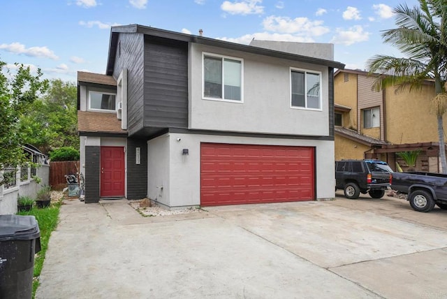 view of front of house with a garage, stucco siding, driveway, and fence