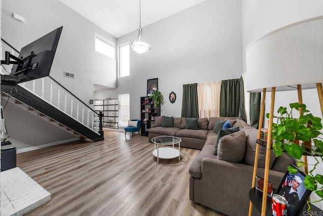 living area with a towering ceiling, wood finished floors, and stairway