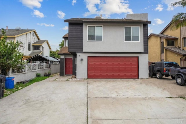 view of front of house with an attached garage, stucco siding, concrete driveway, and fence