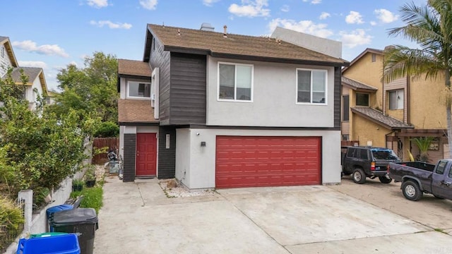 view of front of property featuring an attached garage, driveway, stucco siding, and roof with shingles