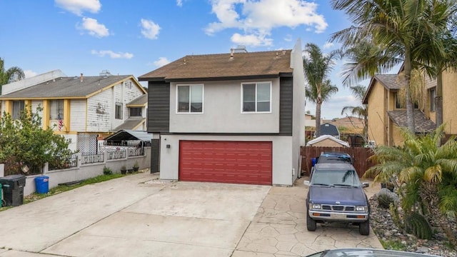 view of front facade featuring stucco siding, a garage, concrete driveway, and fence