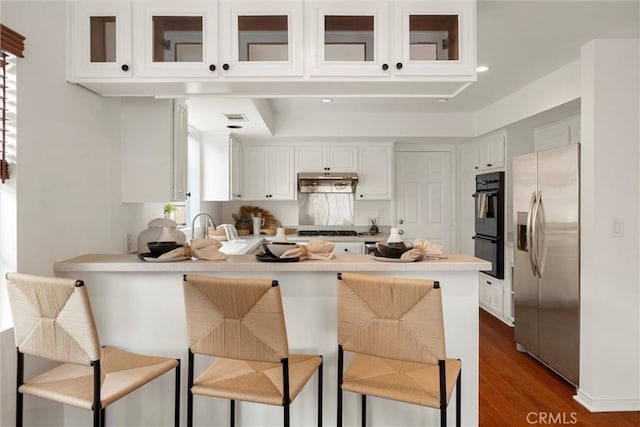 2405 Marshallfield Ln Unit B, Redondo Beach, CA 90278 - kitchen with stainless steel refrigerator with ice dispenser, a peninsula, under cabinet range hood, dark wood-style flooring, and glass insert cabinets