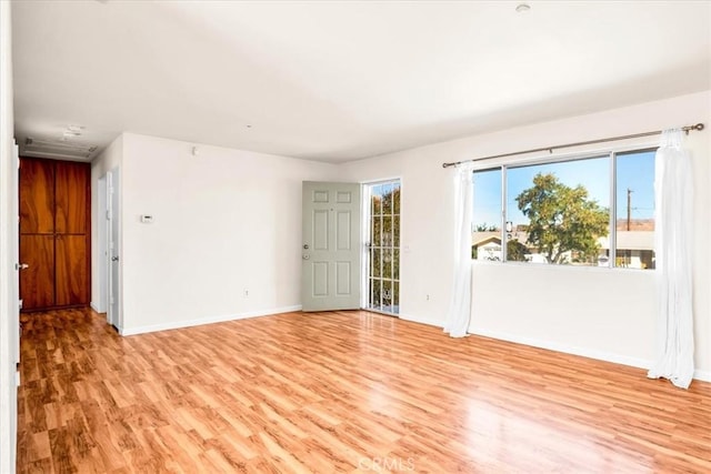 unfurnished room featuring baseboards and light wood-type flooring