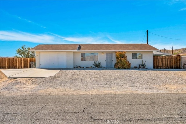 ranch-style home with a garage, fence, and driveway
