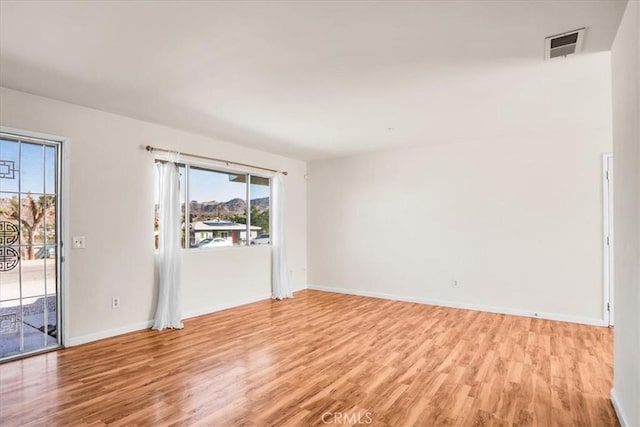 spare room featuring light wood-type flooring and baseboards