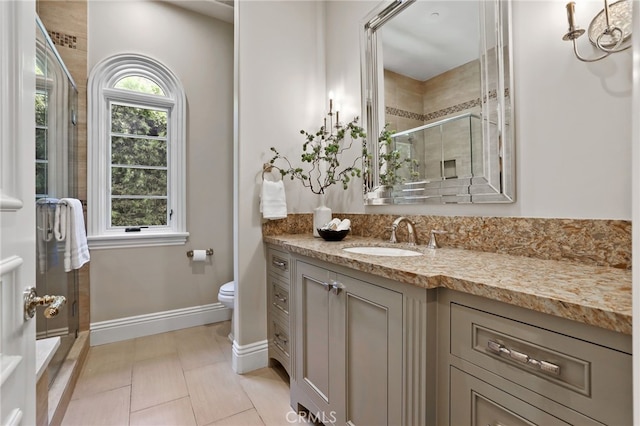 bathroom with a shower stall, toilet, vanity, baseboards, and tile patterned flooring