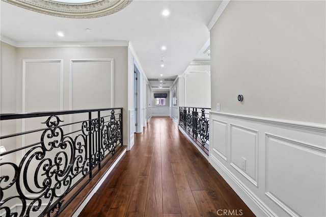 hallway with ornamental molding, recessed lighting, dark wood finished floors, a decorative wall, and wainscoting