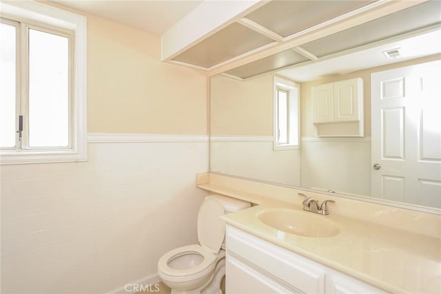 1536 Granicy Dr, Lancaster, CA 93535 - half bathroom featuring toilet, vanity, tile walls, and wainscoting