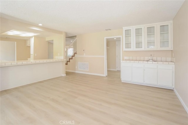 1536 Granicy Dr, Lancaster, CA 93535 - unfurnished room featuring light wood-style flooring, stairs, a sink, a textured ceiling, and baseboards