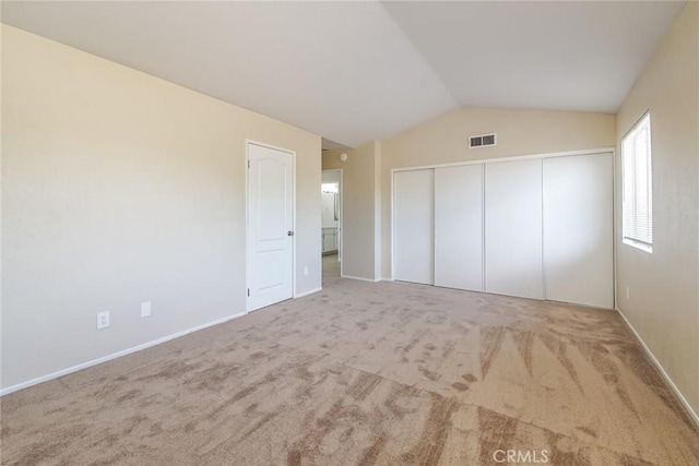 unfurnished bedroom featuring carpet, vaulted ceiling, a closet, and baseboards