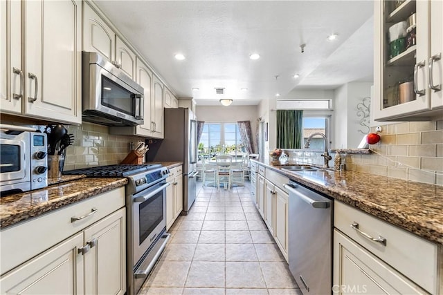4591 Warner Ave Unit 105, Huntington Beach, CA 92649 - kitchen featuring appliances with stainless steel finishes, a sink, backsplash, dark stone countertops, and recessed lighting