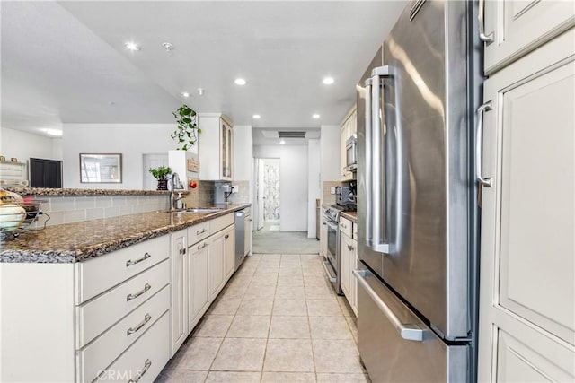 4591 Warner Ave Unit 105, Huntington Beach, CA 92649 - kitchen with appliances with stainless steel finishes, a sink, backsplash, light tile patterned floors, and white cabinets