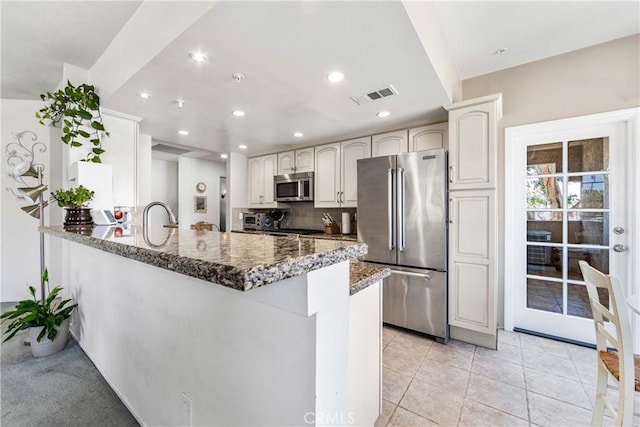 4591 Warner Ave Unit 105, Huntington Beach, CA 92649 - kitchen featuring stainless steel appliances, dark stone countertops, recessed lighting, a peninsula, and tasteful backsplash