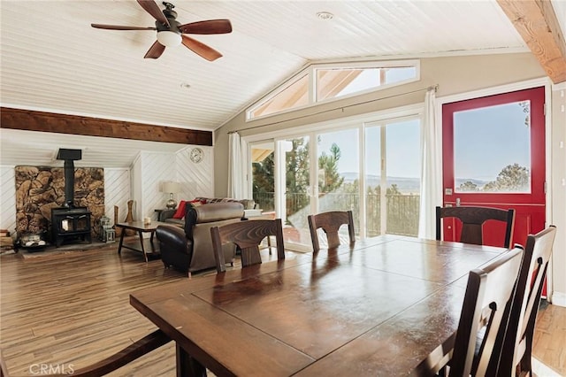 dining area with a wood stove, wood finished floors, and a ceiling fan