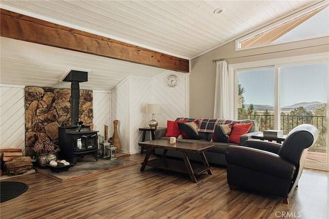 living area featuring vaulted ceiling, wood finished floors, a wood stove, wooden ceiling, and wood walls
