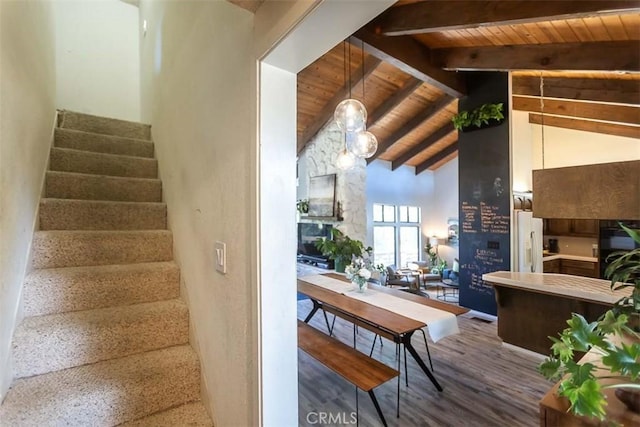 stairway with beamed ceiling, wooden ceiling, high vaulted ceiling, and wood finished floors