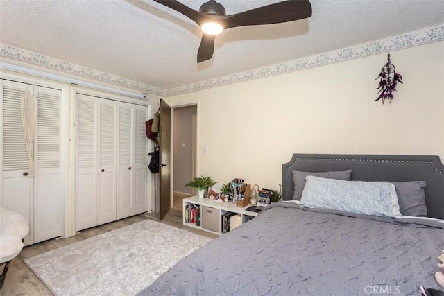 bedroom featuring wood finished floors, a textured ceiling, ceiling fan, and multiple closets