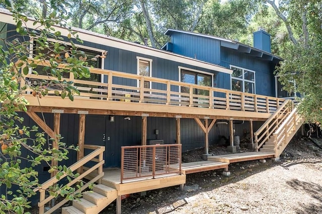 rear view of house featuring a deck, a chimney, and stairway