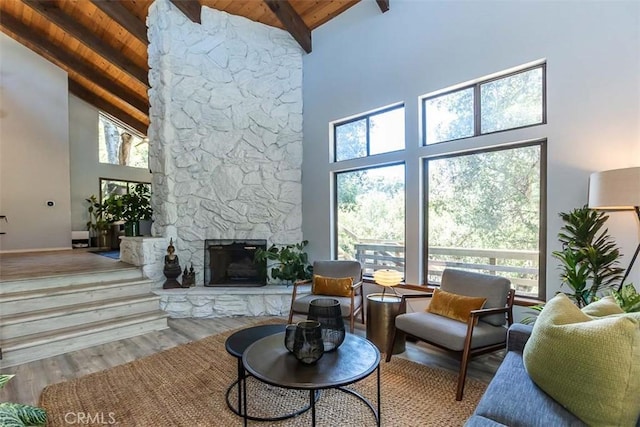 living room with high vaulted ceiling, wooden ceiling, beamed ceiling, a fireplace, and wood finished floors