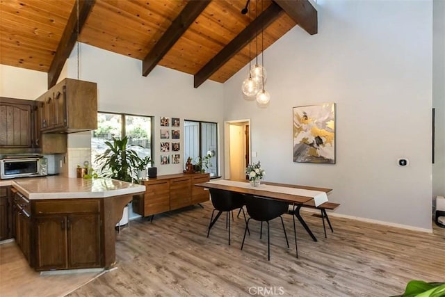 dining area with light wood-type flooring, beam ceiling, high vaulted ceiling, wooden ceiling, and baseboards