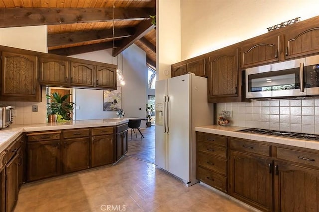 kitchen with stainless steel appliances, tile countertops, beam ceiling, wooden ceiling, and decorative backsplash