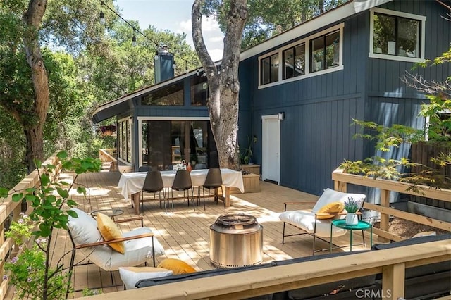 rear view of house featuring a wooden deck, a fire pit, and a chimney